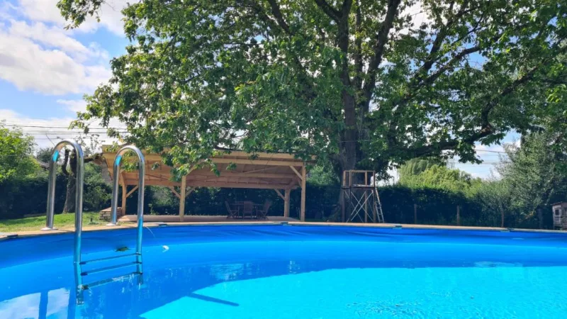 Piscine privative à l'ombre d'un grand chêne, avec préau en bois et espace détente