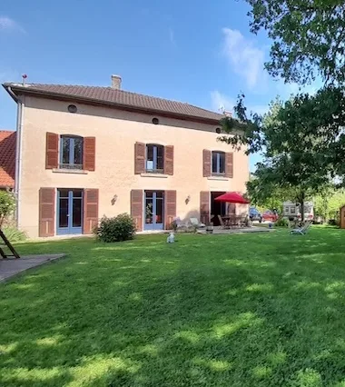 Gîte de groupe Le Grenier du Chêne à Saint-Étienne-sur-Reyssouze — Façade en pierre de la maison bressane entourée d'un grand jardin arboré et engazonné, capacité 15 personnes