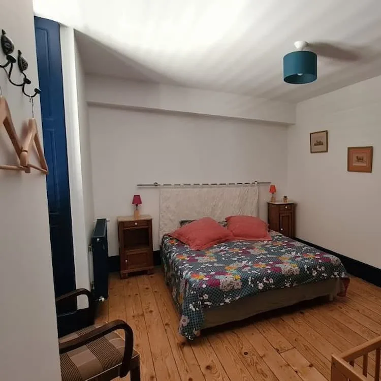 Chambre double avec grand lit fleuri, porte-fenêtre donnant sur le jardin