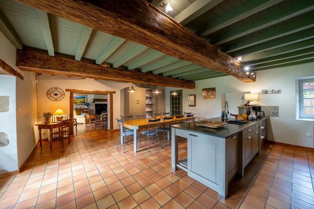 Salle à manger sous poutres apparentes avec grande table en bois pour les repas de groupe