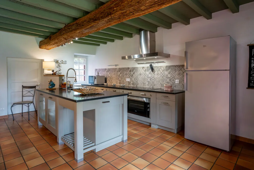 Cuisine américaine avec îlot central, plan de travail noir et carrelage à motifs
