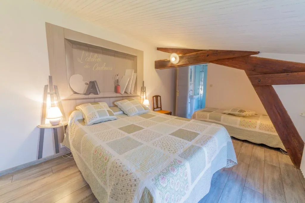 Chambre l'Atelier des Couleurs avec grand lit double et lit simple sous les poutres