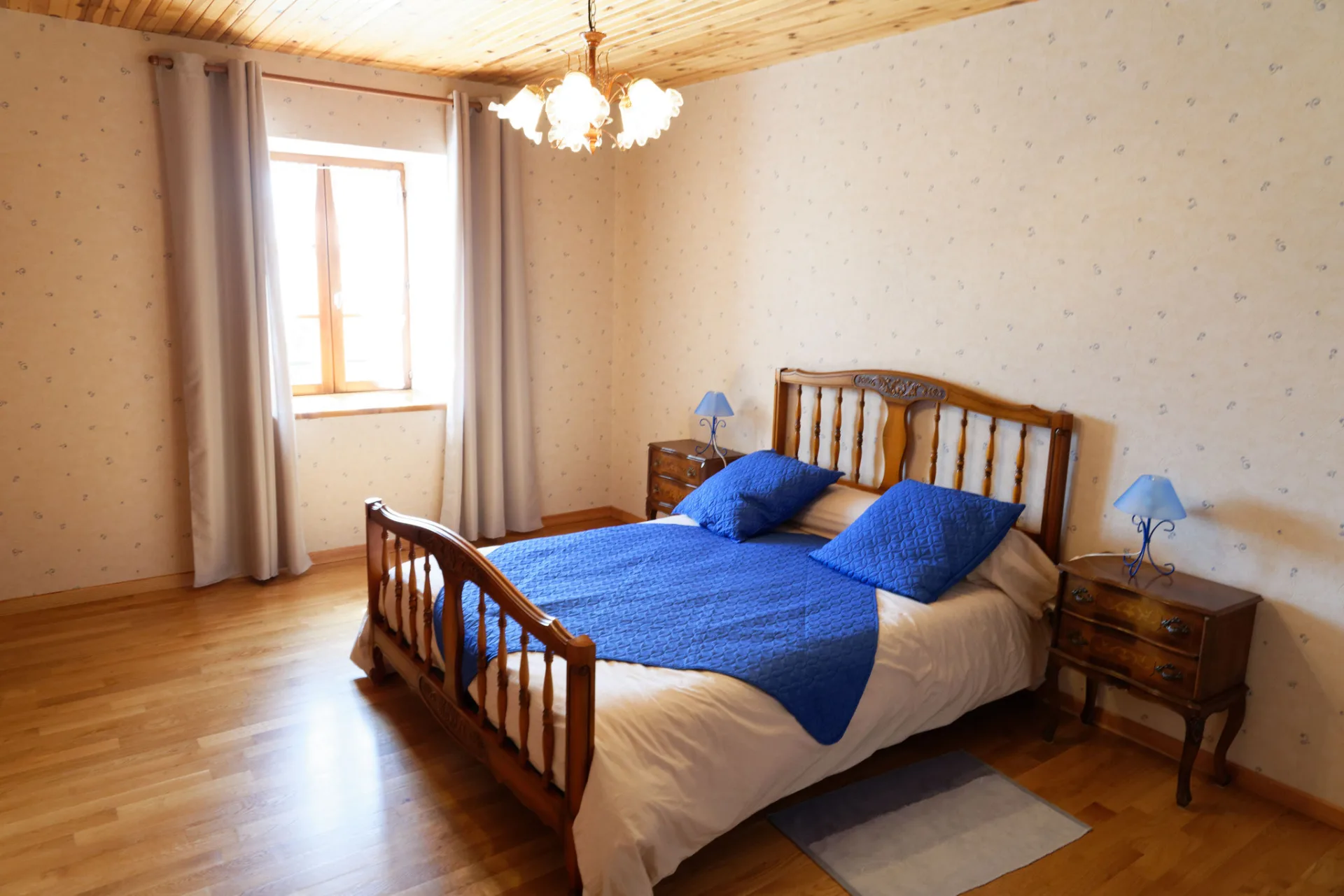 Chambre double avec literie bleue sous poutres apparentes