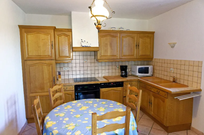 Cuisine équipée en bois avec table ronde et nappe à motifs de citrons