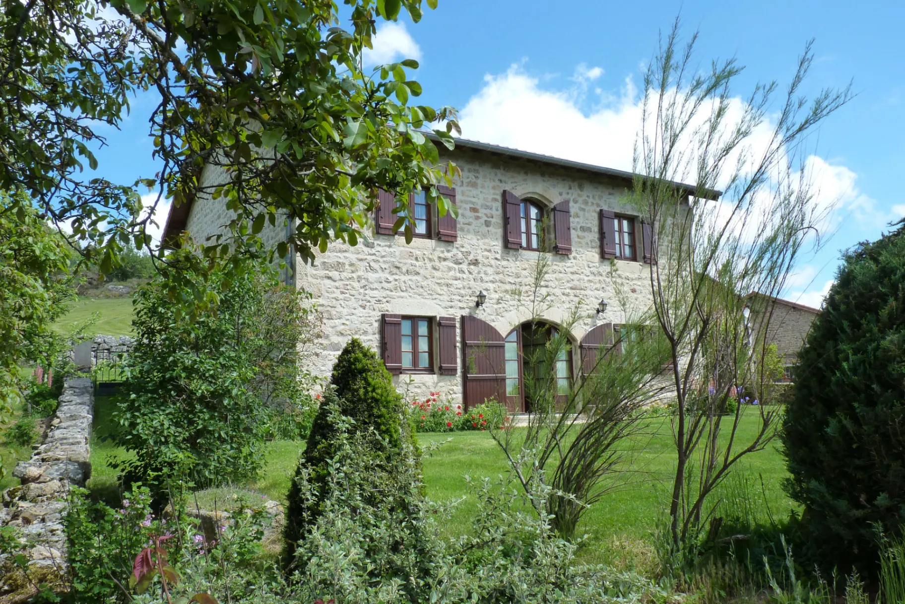 Gîte de groupe Gîte Les Lilas à Montarcher — Façade en pierre du gîte Les Lilas couverte de lierre, entourée d'un jardin arboré, capacité 12 personnes