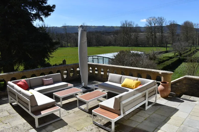Terrasse en pierre avec salons de jardin et vue dégagée sur la vallée de l'Aveyron