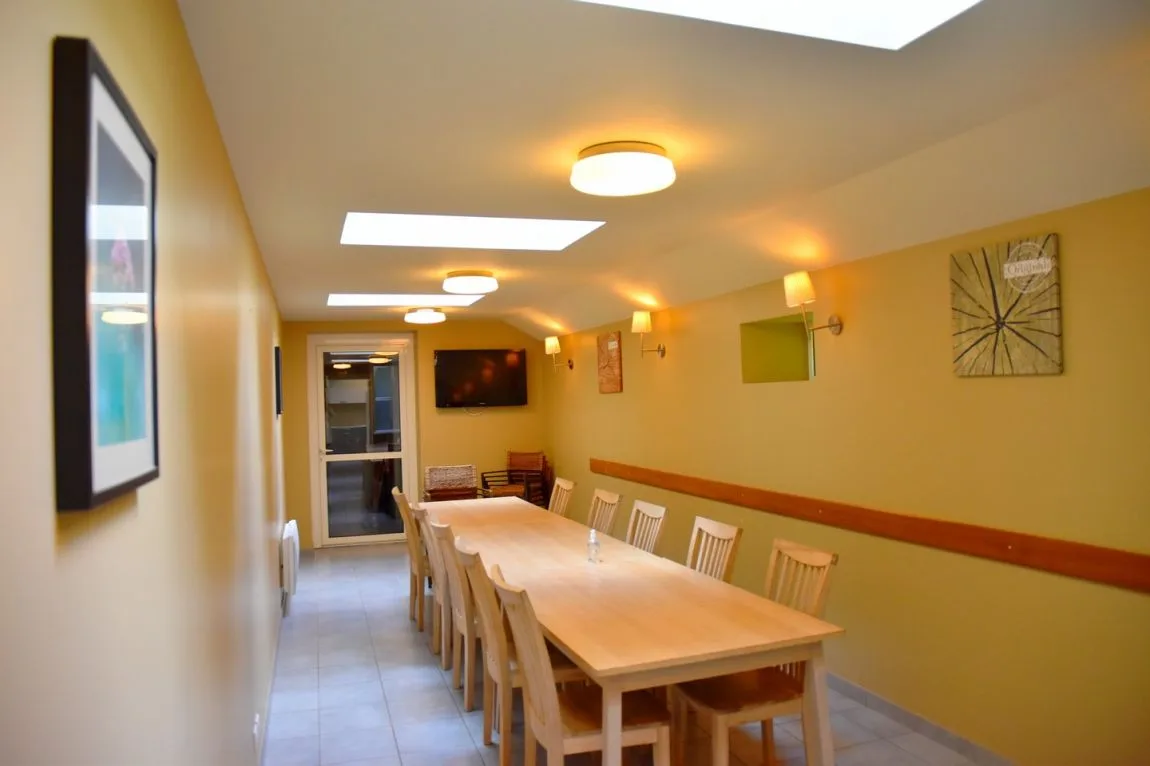 Grande salle à manger commune avec longue table en bois pour 15 personnes