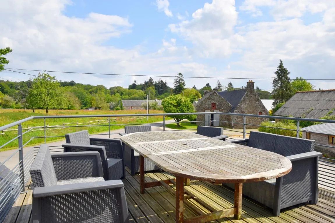 Terrasse en bois surélevée avec table et chaises, vue sur le pré et les chevaux