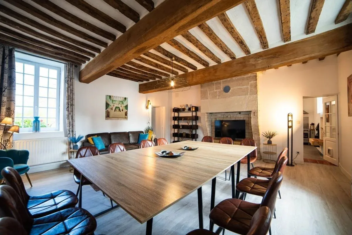 Salle à manger sous poutres apparentes avec longue table en bois et cheminée