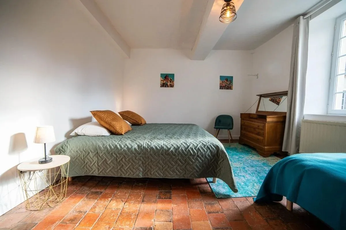 Chambre au sol en tomettes avec literie vert et moutarde et mobilier ancien