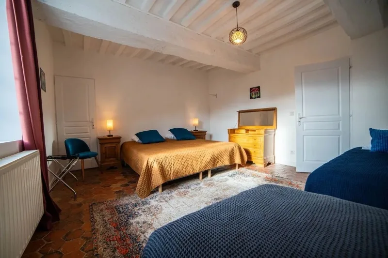 Chambre avec lit double et lit simple, sol en tomettes et poutres apparentes peintes en blanc