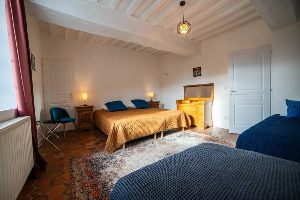Chambre avec lit double et lit simple, sol en tomettes et poutres apparentes peintes en blanc