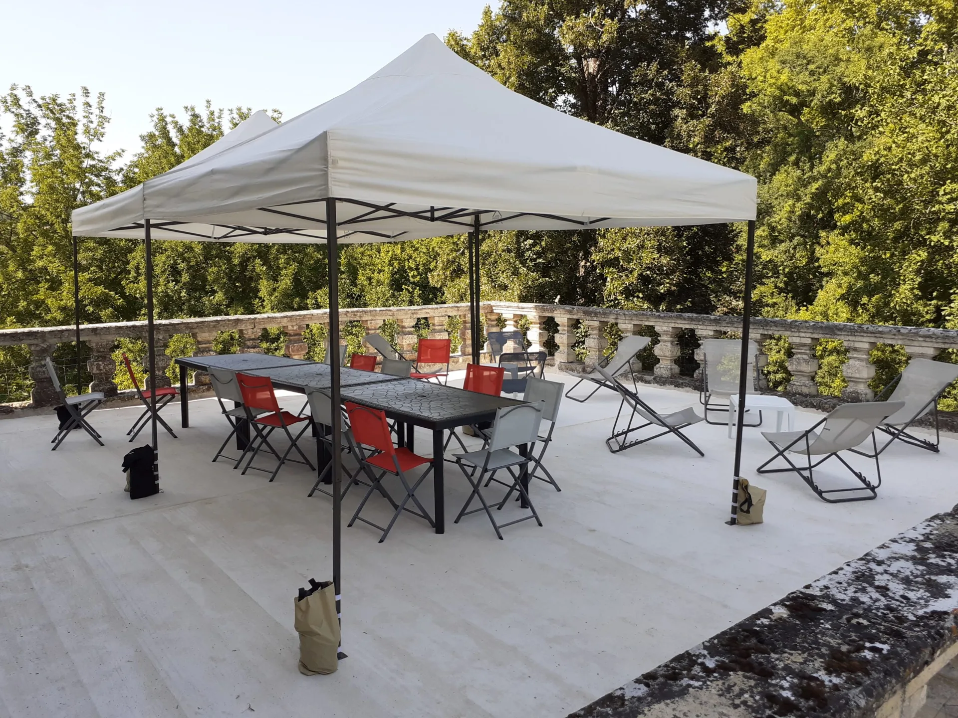 Terrasse en pierre avec barnums, tables et chaises longues pour profiter du parc