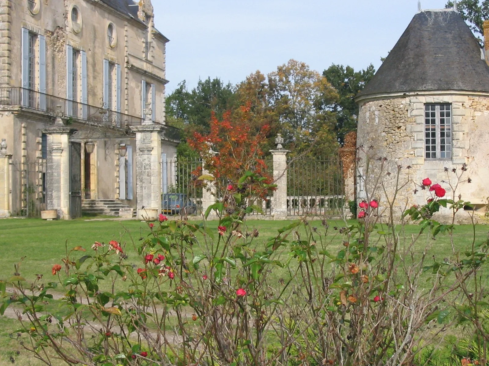 Vue sur la façade principale et la tourelle ronde depuis le parc, avec grille d'entrée