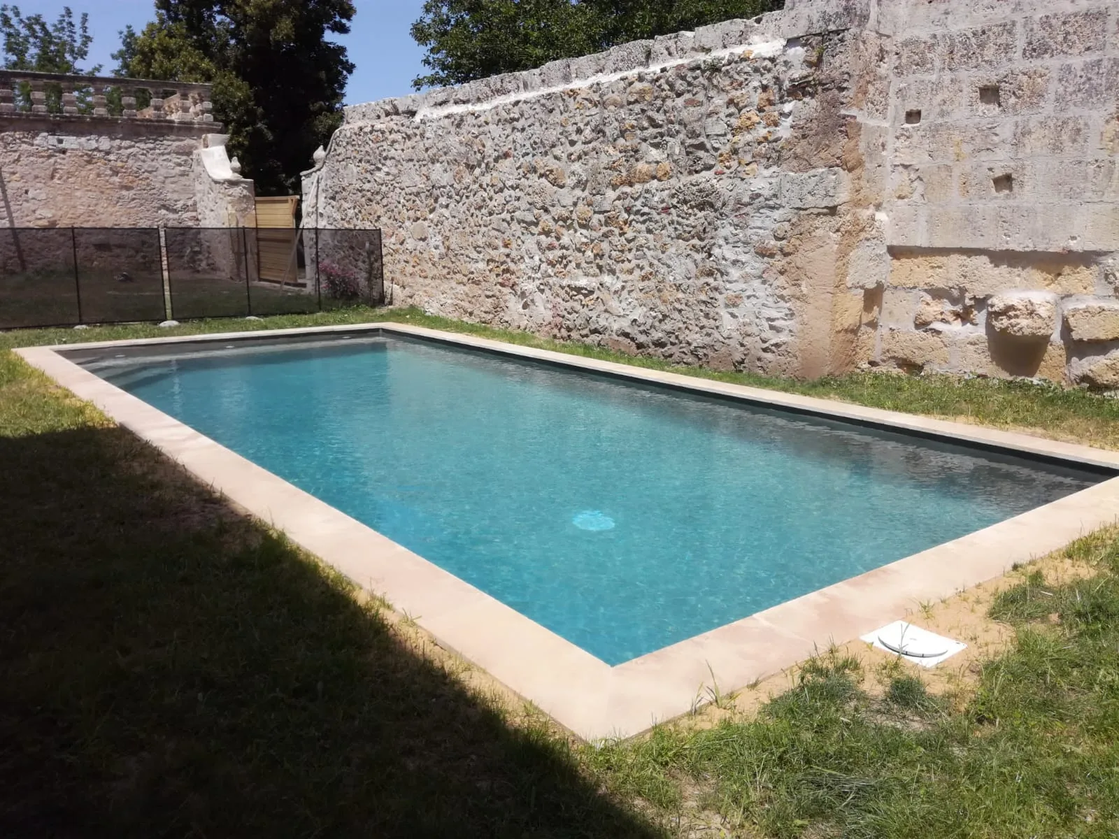 Piscine privée sécurisée dans une cour close entourée de murs en pierre