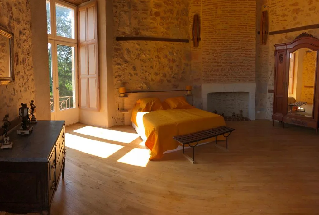 Chambre de la Tour baignée de lumière, avec lit double, cheminée et accès balcon