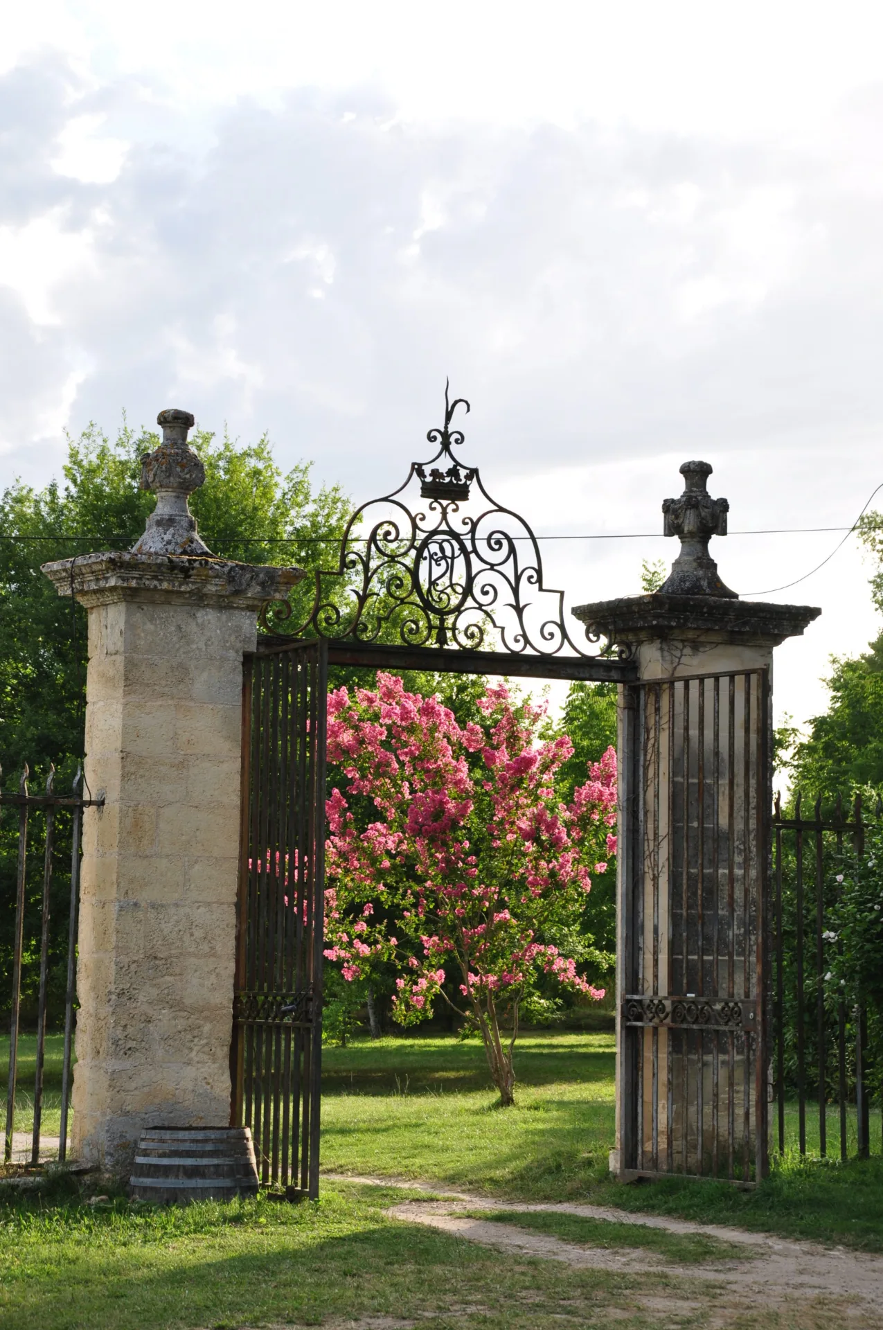 Portail en fer forgé ancien ouvrant sur le parc arboré du château