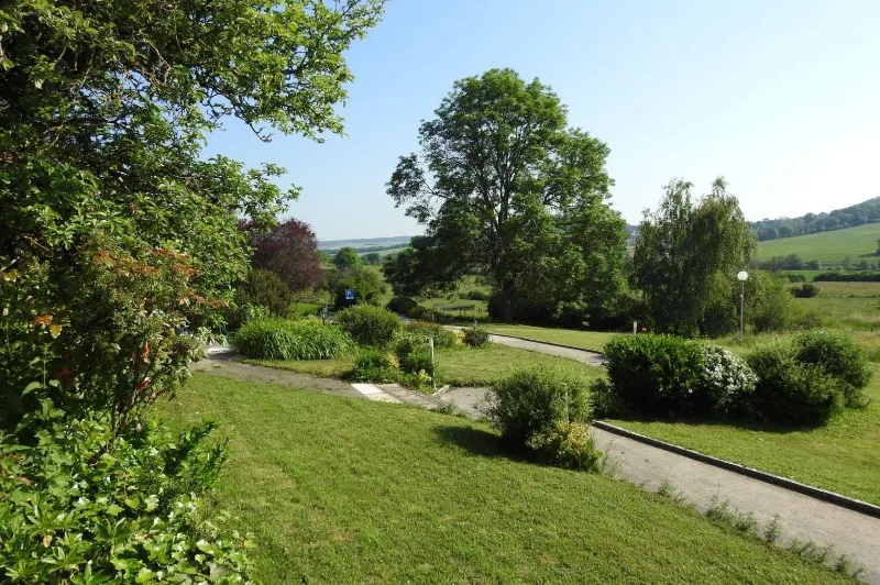 Jardin arboré et allée verdoyante du domaine avec vue dégagée sur les collines