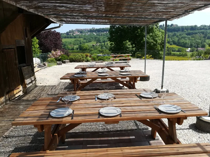 Grande terrasse extérieure couverte avec tables dressées pour un groupe, vue panoramique