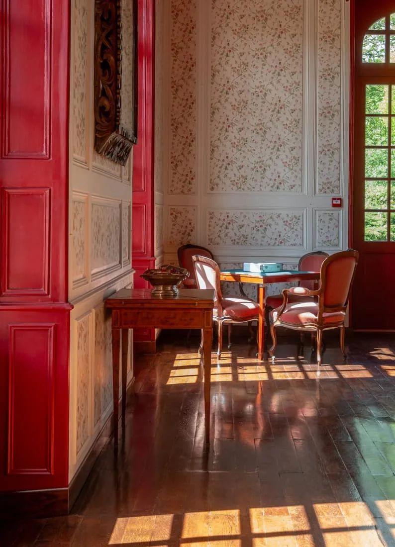 Salon aux boiseries rouges et mobilier d'époque, lumière naturelle