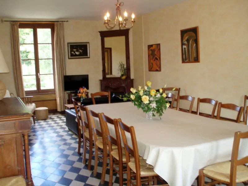 Salle à manger avec longue tablée en bois dressée pour 15 convives