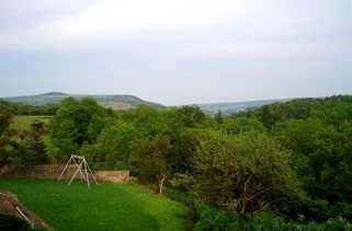 Vue sur le jardin arboré avec balançoire depuis la propriété