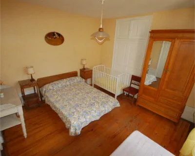 Chambre avec grand lit double, armoire ancienne en bois et parquet