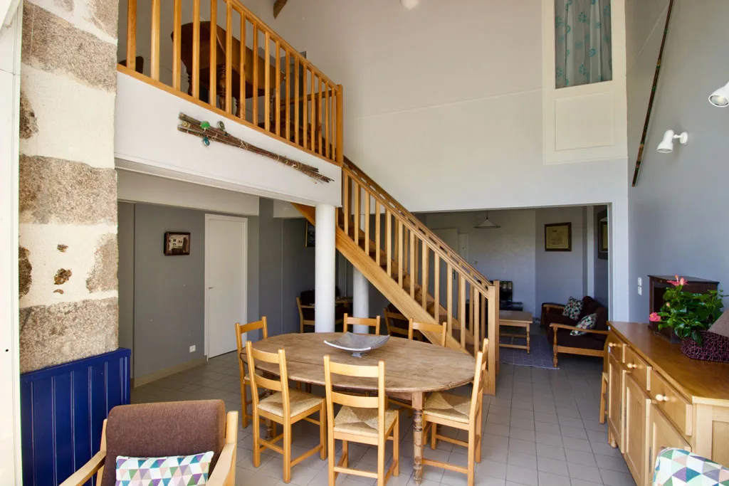 Salle à manger commune sous la mezzanine avec grande table ronde en bois