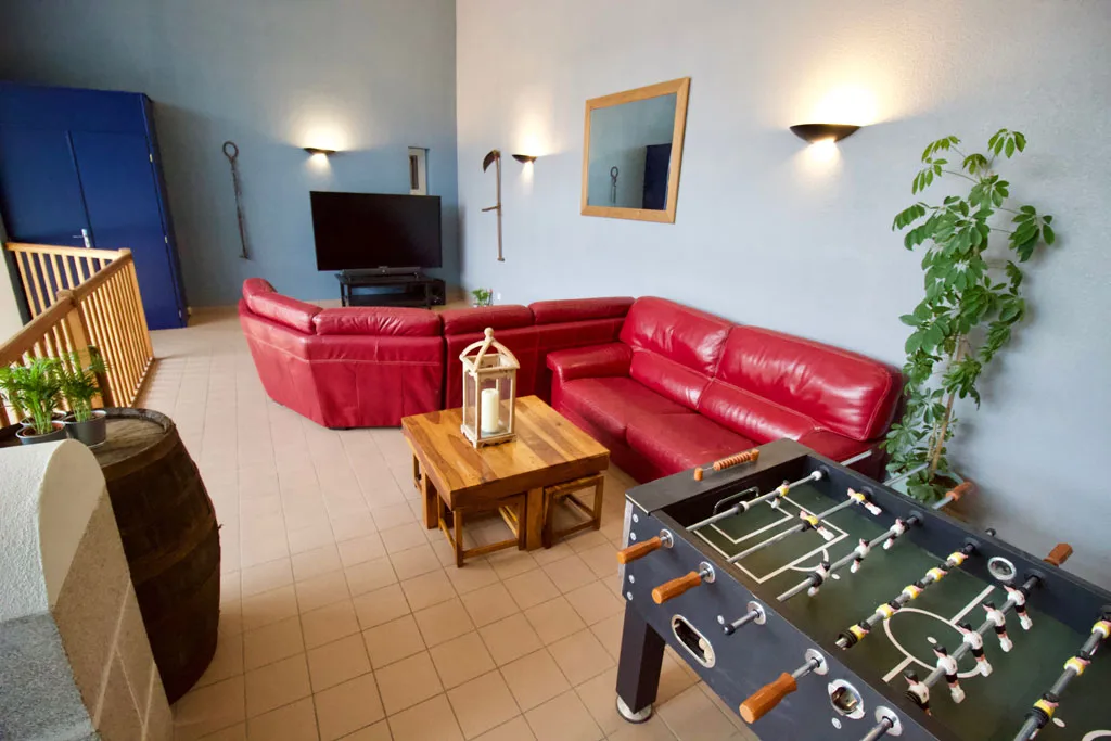 Salon de détente avec canapés en cuir rouge et baby-foot