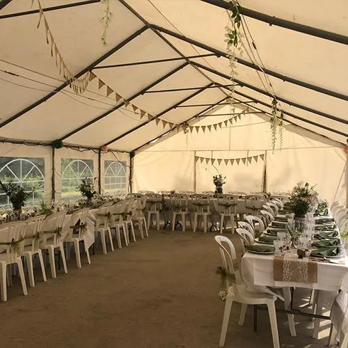 Tente de réception aménagée avec grandes tables pour événements de groupe