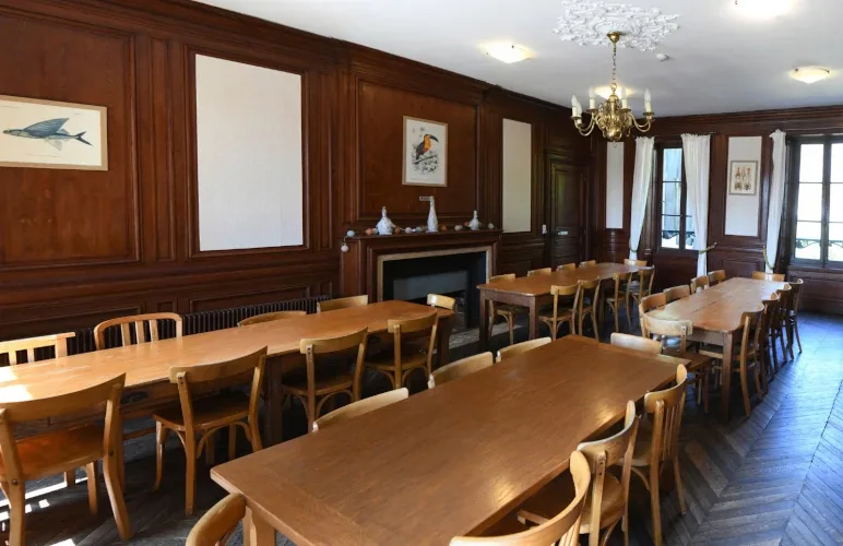 Salle à manger boisée du château avec grandes tables pour repas de groupe