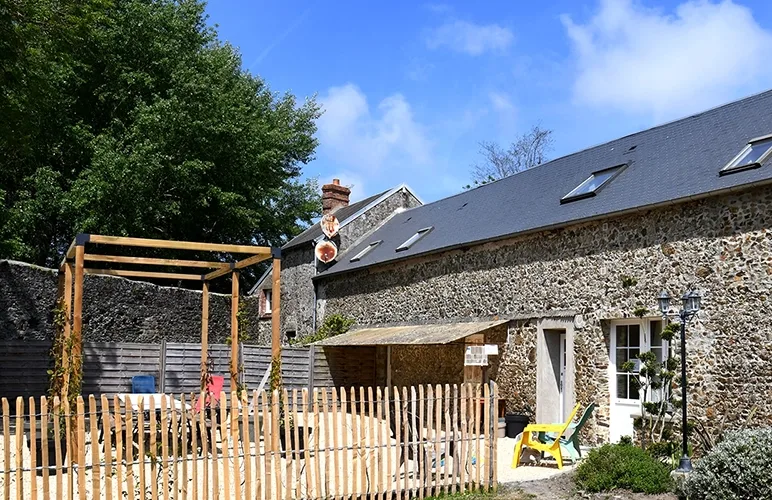 Bâtiment en pierre du gîte l'écurie avec cour extérieure et clôture bois