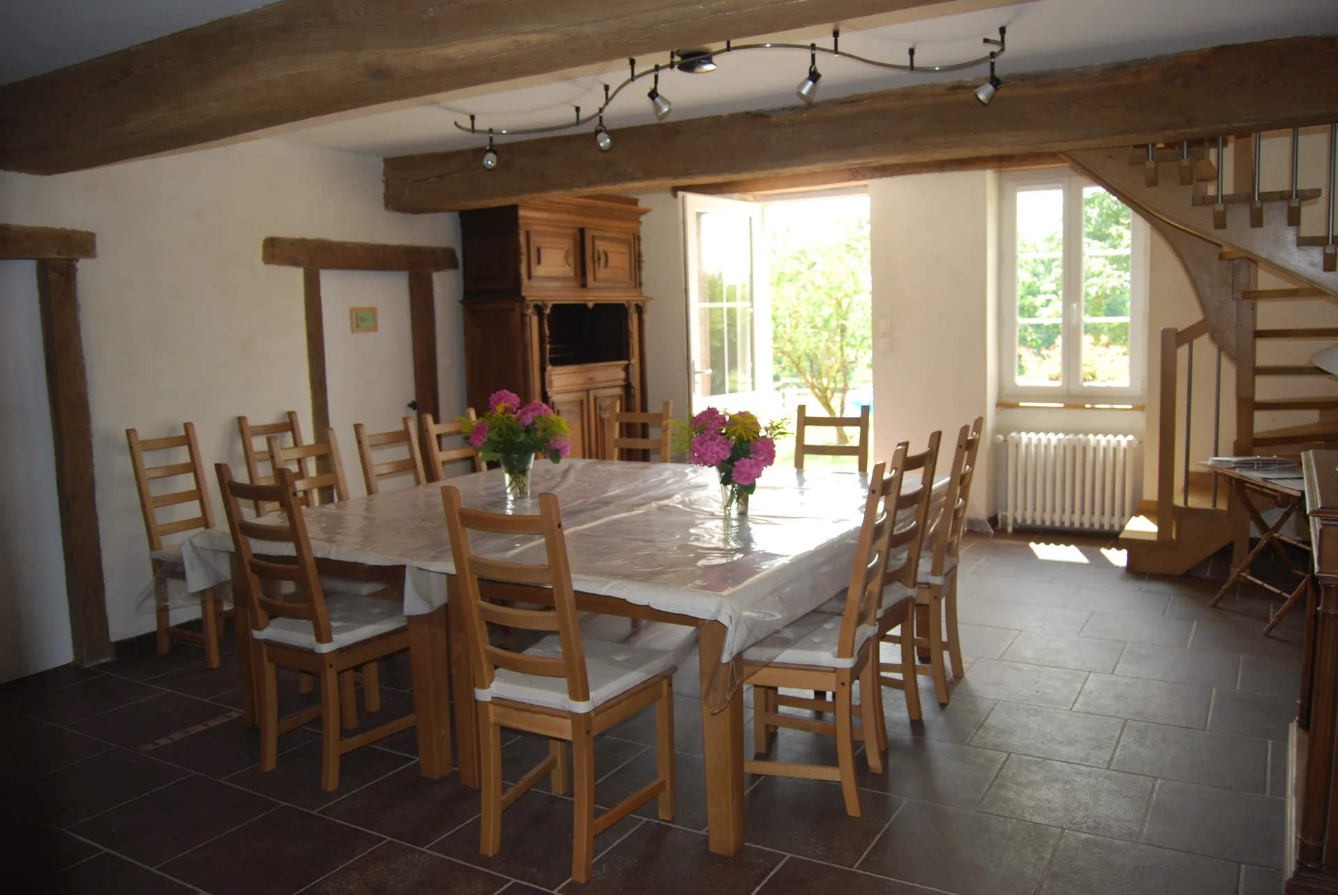 Gîte de groupe Gîte des Chambauds à Buxières-les-Mines — Grande salle de séjour lumineuse avec poutres apparentes et coin repas pour 12 personnes, capacité 12 personnes