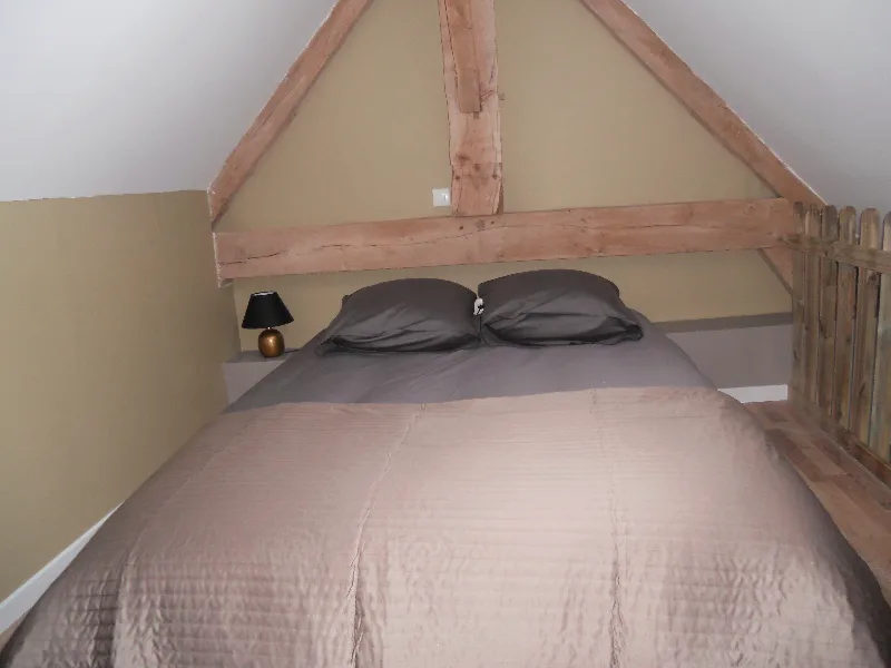 Chambre en mezzanine sous charpente apparente avec grand lit double