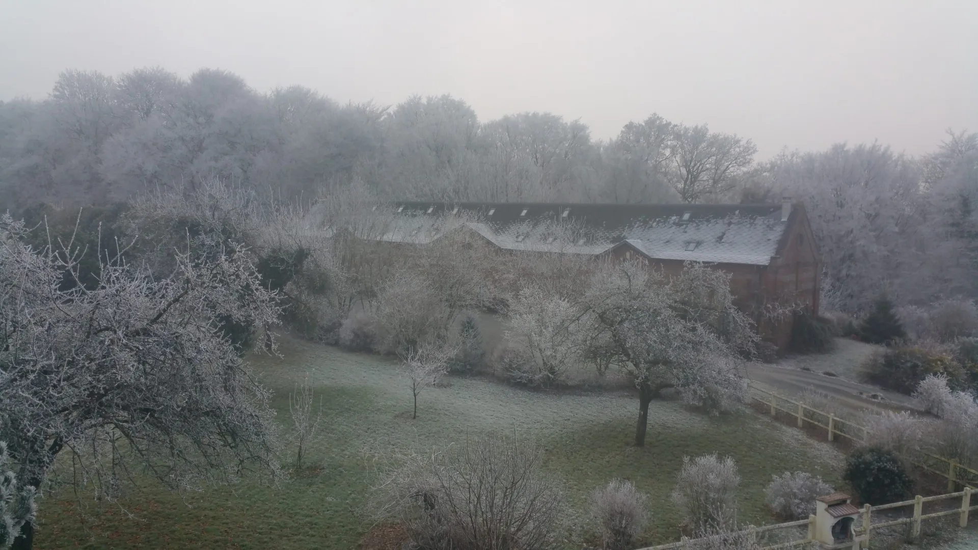 Vue hivernale du domaine givré avec la longère et son parc arboré