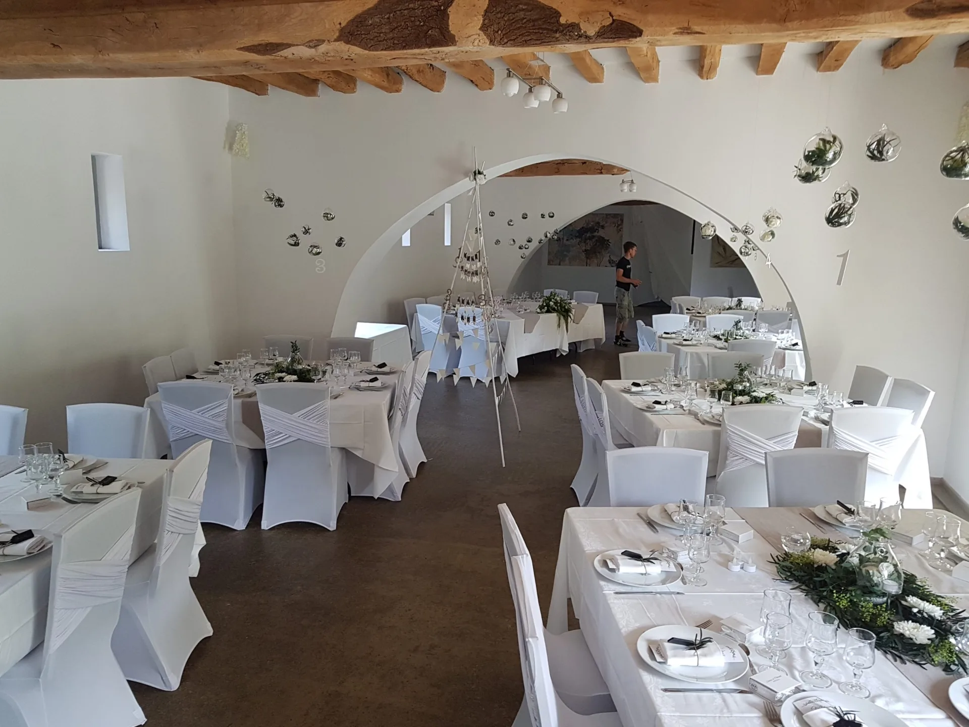 Salle de réception décorée pour un mariage avec tables rondes et suspensions en verre