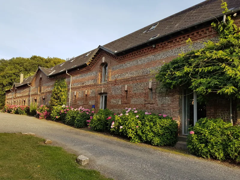 Façade en briques et silex du Clos de la Beauce, longère normande du XVIIIe siècle fleurie d'hortensias