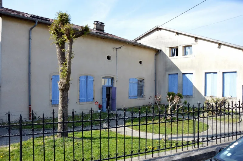 Façade du gite Les Flaviottes avec volets bleus et jardin clôturé