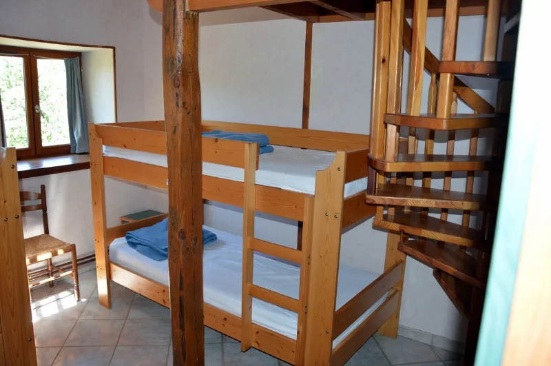 Chambre avec lits superposés en bois et escalier en colimaon menant à l'étage