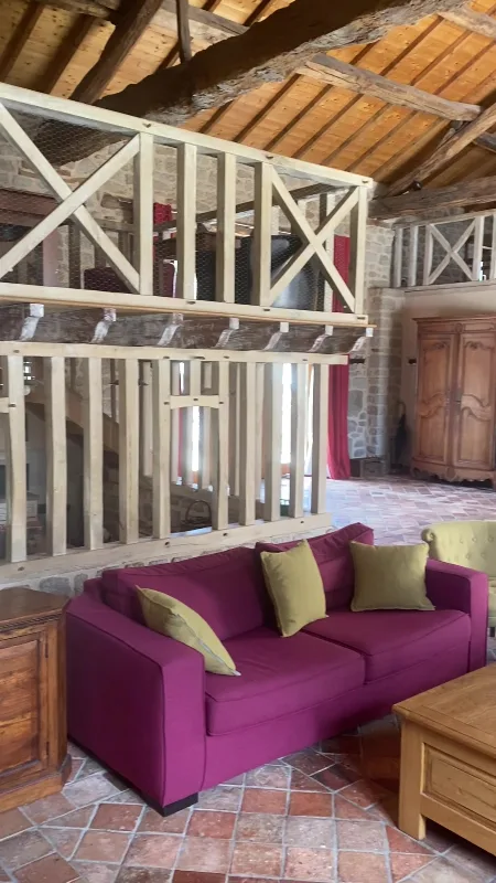 Coin salon en mezzanine avec canapés bordeaux et armoire ancienne en bois