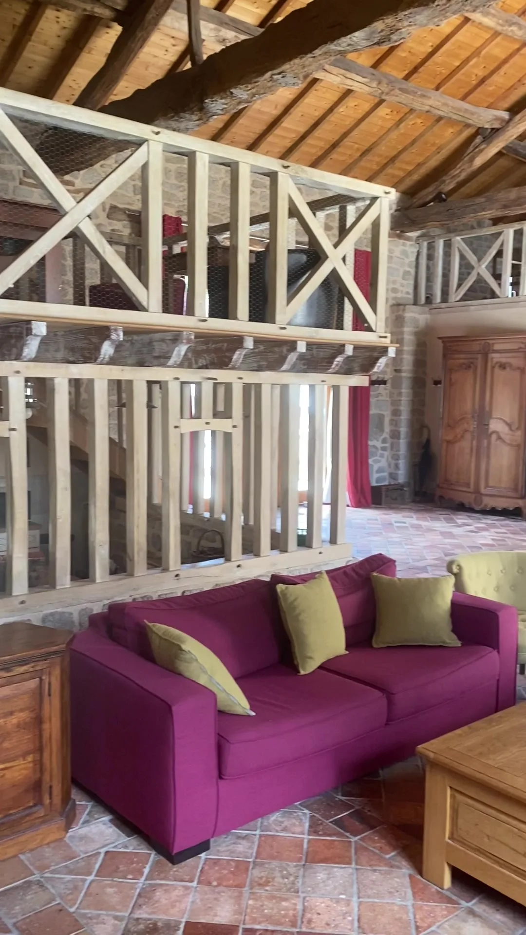 Coin salon en mezzanine avec canapés bordeaux et armoire ancienne en bois