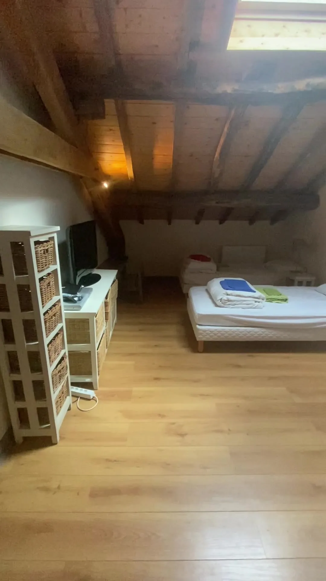 Dortoir sous les combles avec plusieurs lits simples et poutres en bois
