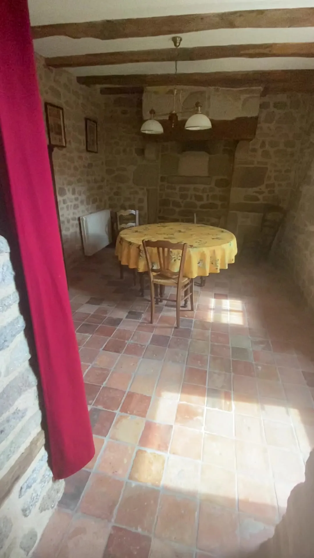 Salle à manger voûtée en pierre avec table ronde et rideau rouge