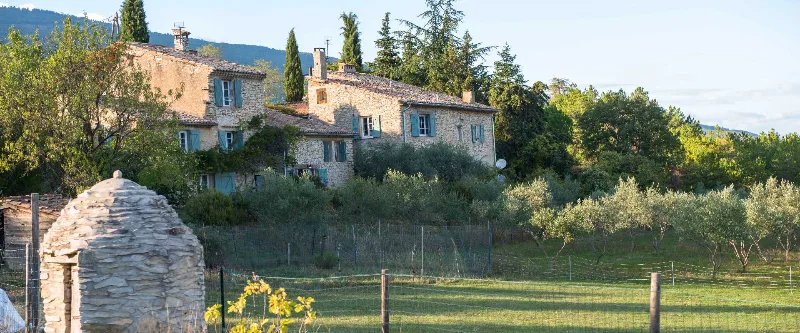 Vue d'ensemble des bâtisses en pierre du domaine entourées d'oliviers et de collines