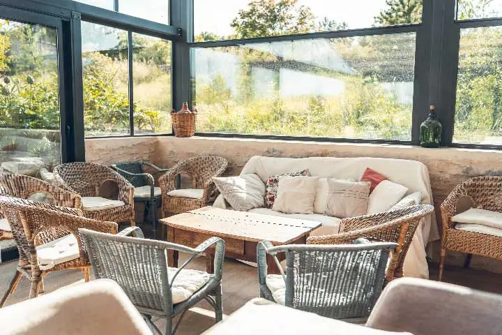 Véranda salon avec fauteuils en rotin et vue sur la campagne provençale