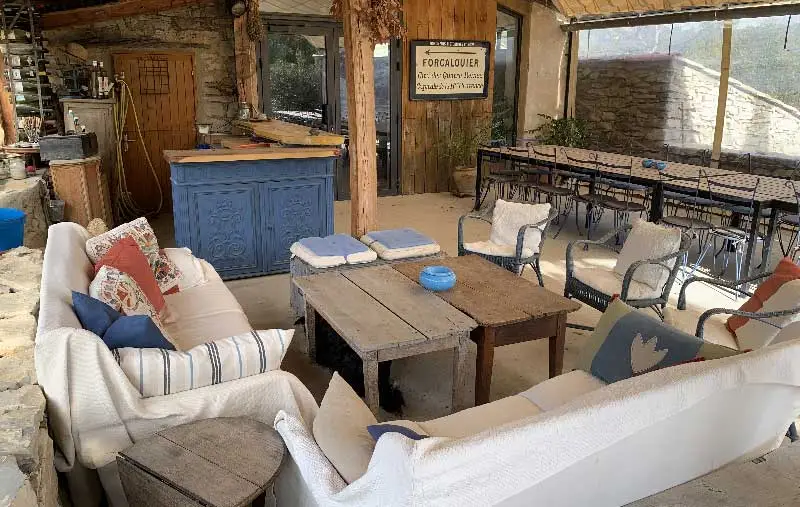 Bar et coin salon couvert avec canapés et grande tablée sur la terrasse