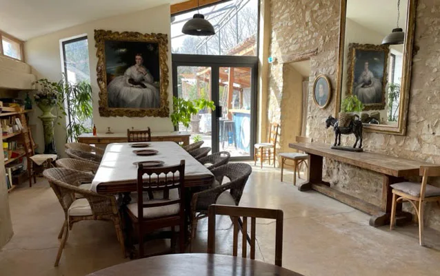Grande salle commune avec longue table en bois, pierres apparentes et cheminée provençale