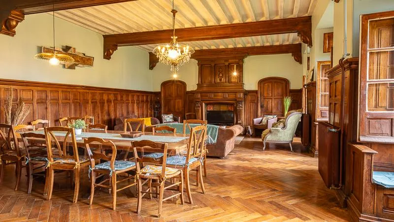 Grande salle à manger et salon avec cheminée en pierre, poutres apparentes et boiseries anciennes