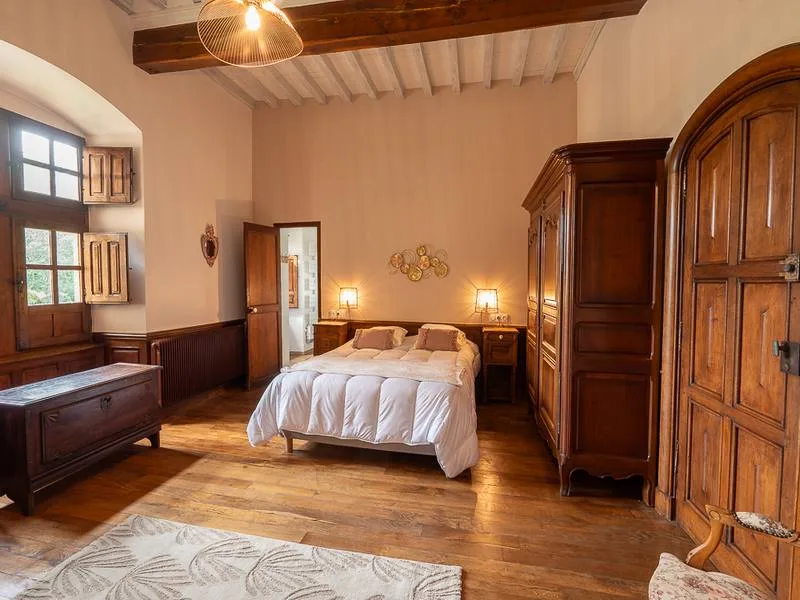 Chambre avec lit double, armoire ancienne en bois et poutres au plafond