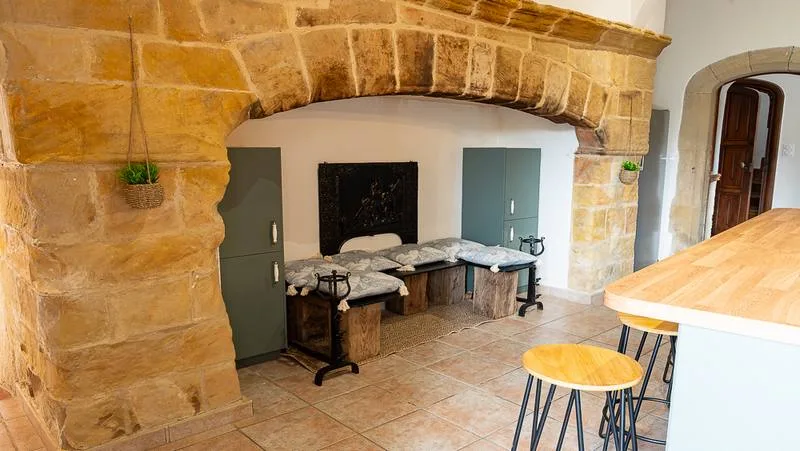 Cuisine voûtée en pierre avec coin banquette, plan de travail en bois et tabourets hauts